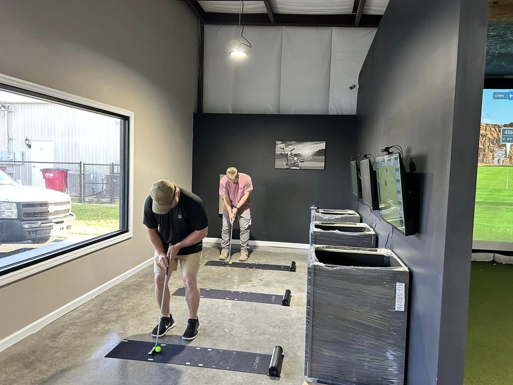 Golfers practicing in a simulator bay